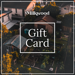 Milkwood Gift Card displayed over an aerial view of a lush backyard garden with greenhouses and garden beds, framed by homes and trees in soft, evening light. The Milkwood logo is at the top, and 'Gift Card' is prominently displayed in the centre in white text.